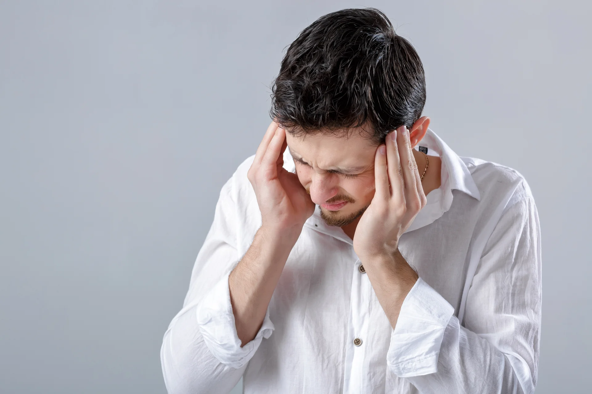 Frustrated man standing and touching his head in a sign of pain