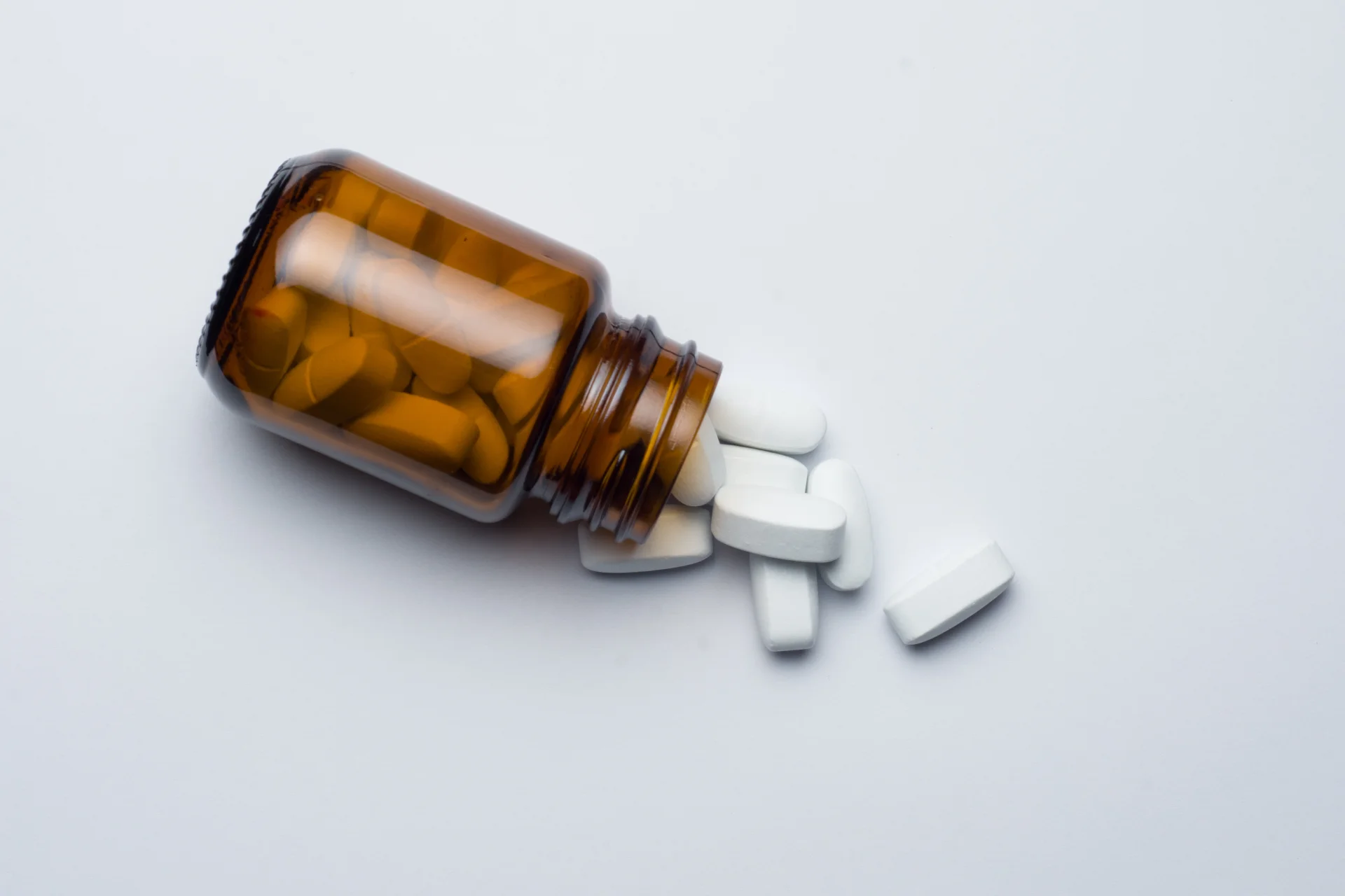 medicine pill tablet in bottle and spilled on table with white background