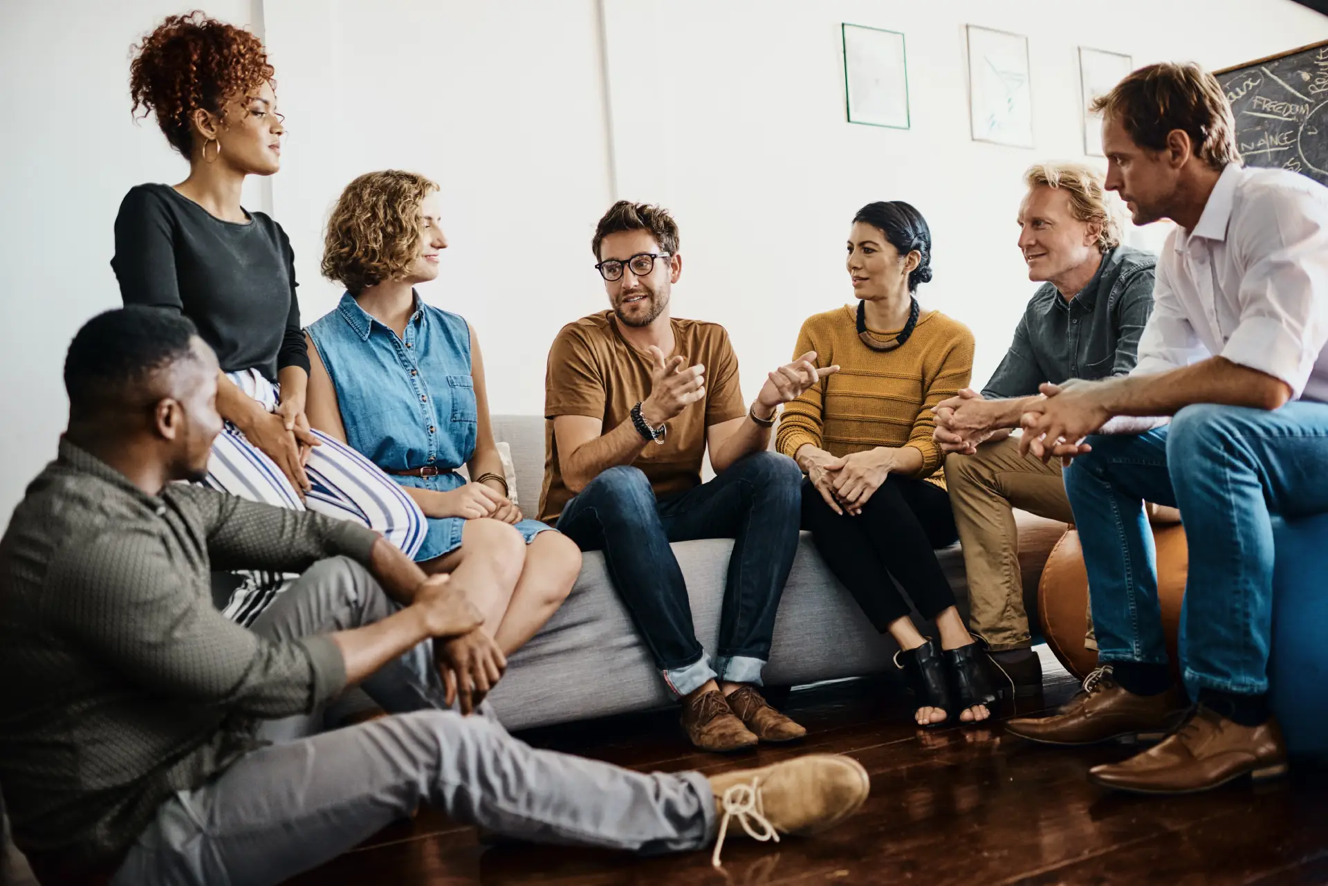 A small group gathered at an evening 12-Step meeting, sitting in a circle and supporting one another.